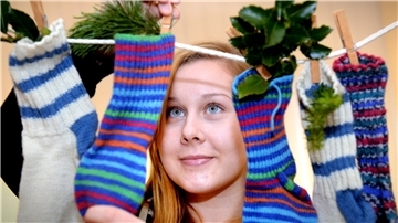 Eine Frau hängt Socken mit kleinen Präsenten an eine Leine