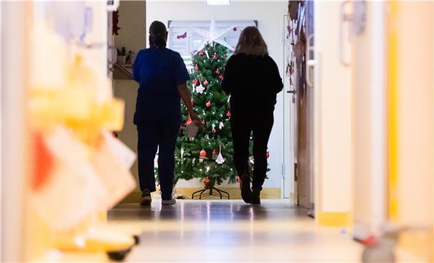 So wird es auch am Krankenbett zu Weihnachten etwas festlich Zwei Krankenpfleger im Krankenhaus mit einem Weihnachtsbaum