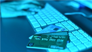 Finger auf eine Computertastatur, davor Kreditkarten. In Nordenham stand ein Mann wegen Internet-Betrugs vor Gericht.