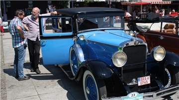 Zwei Männer stehen neben einem Oldtimer.
