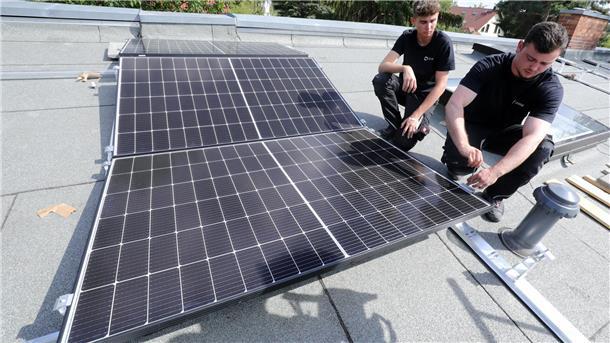 Arbeiter installieren Solarpaneele auf einem Dach.