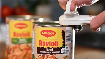 Zwei Dosen Ravioli, eine wird gerade mit einem weißen Dosenöffner geöffnet.