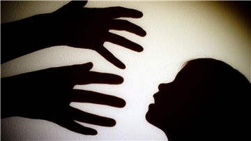 Schatten von Händen einer erwachsenen Person und dem Kopf eines Kindes an einer Wand eines Zimmers