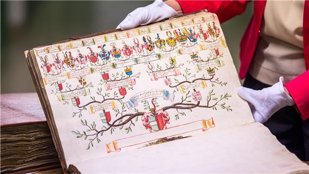 Margit Ksoll-Marcon, Generaldirektorin der Staatlichen Archive Bayerns, hält im Archivraum des Staatsarchivs ein Buch mit einem alten Stammbaum. 