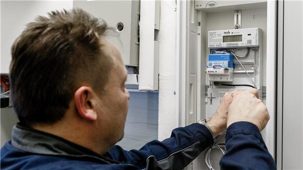 Ein Elektriker montiert einen digitalen Stromzähler mit einem Smart-Meter-Gateway zur Datenübertragung. 