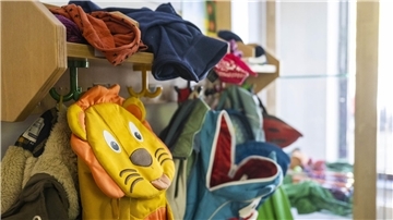 Rucksäcke hängen an einer Garderobe einer Kita.