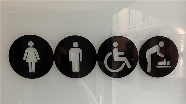 Zeichen an einer Toilettentür für Frauen, Männer, Behinderte und Wickelmöglichkeit für Babys