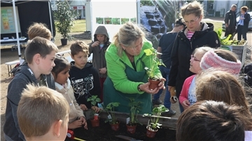 Kinder gärtnern mit Erwachsenen an einem Hochbeet