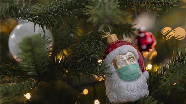 Ein Weihnachtsbaum mit der Christbaumkugel eines Weihnachtsmanns mit OP-Maske.