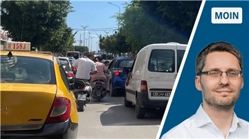 Dichter Verkehr auf einer Straße in Tunesien. Zu sehen ist ein gelbes Taxi , Lieferwagen, Autos und Mopedfahrer.