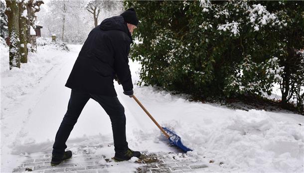 Schneeräumpflicht - Was Sie beachten müssen Ein Mann schaufelt Schnee mit einem Schneeschieber.