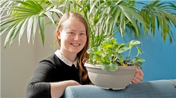 Wiebke Lammers hält einen Topf mit Erdbeerpflanzen in der Hand.