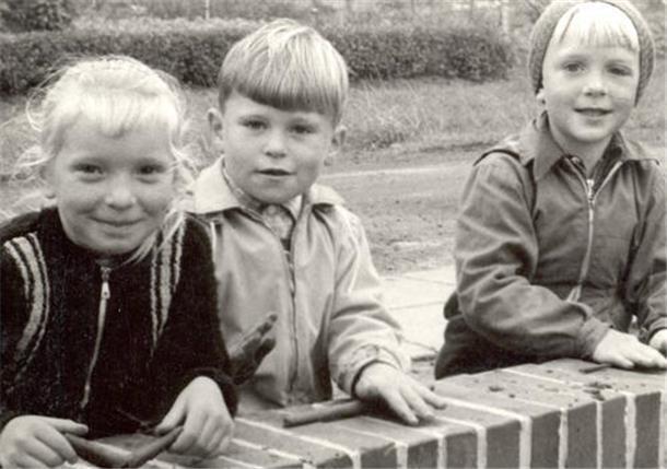 Wo haben die fröhlich über eine Mauer schauenden Kinder denn den Ton her, den sie gerade zu Würstchen ausrollen? Doch nicht etwa von der Baustelle?