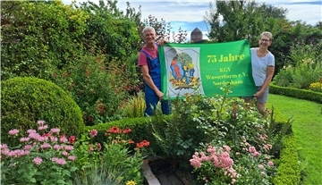 Bild von Wolfgang Engels, Vorsitzender des Kleingartenvereins Wasserturm in Nordenham, und seiner Frau Jutta mit einem Banner zum 75-jährigen Bestehen des Vereins.