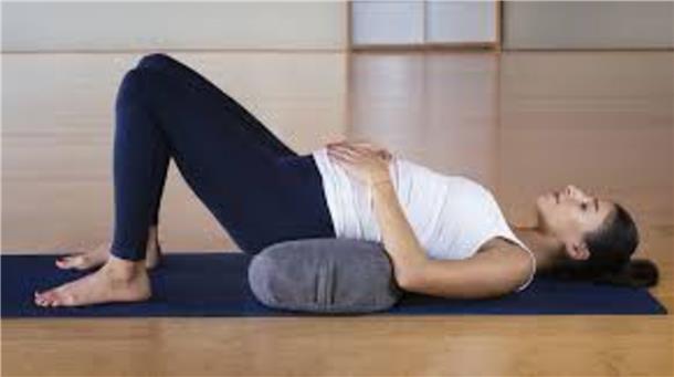Eine schwangere Frau liegt auf dem Boden und macht Yoga.