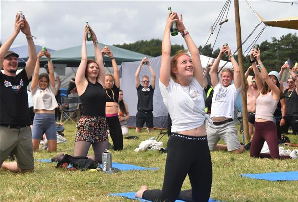 Insider-Tipps für das Deichbrand-Festival 2024: So holt ihr das Maximum raus! Menschen auf dem Deichbrand-Festival, die Bier-Yoga machen.