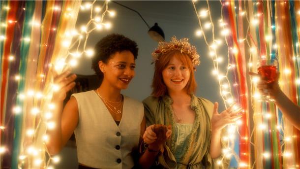 Zara (Alina Sokhna, l) und Olja (Valeriia Berezovska) feiern mit ihren Mitbewohnern Oljas und Petjas Hochzeit in einer Szene des ZDF-Projekts „Himmel & Erde“.