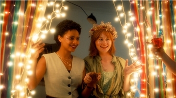 Zara (Alina Sokhna, l) und Olja (Valeriia Berezovska) feiern mit ihren Mitbewohnern Oljas und Petjas Hochzeit in einer Szene des ZDF-Projekts „Himmel & Erde“.