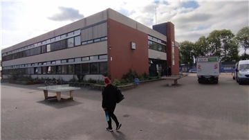 Eine Frau geht vor einem Schulgebäude entlang.