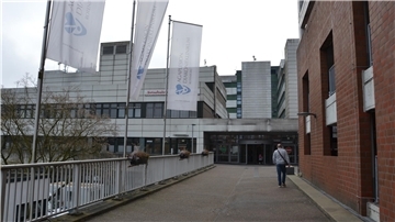 Ein hohes Gebäude im Hintergrund und ein Fußweg zu einem Eingang.
