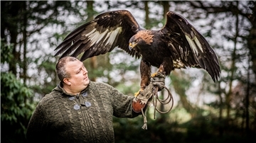 Ein Mann hält einen Adler auf der Hand. 