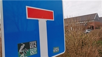Sackgassenschild im Vordergrund, dahinter ein Gebäude