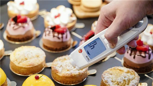 Lebensmittelkontrolleur beim Landratsamt Rhein-Neckar-Kreis in der Abteilung Veterinäramt und Verbraucherschutz, hält in einer Patisserie bei einer Kontrolle ein Thermometer an eine kleine Torte.