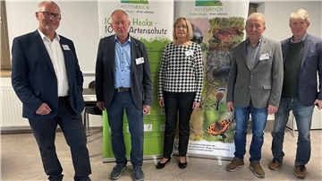 Vier Männer und eine Frau stehen nebeneinander vor großen Aufstellern über Hecken und Artenschutz.