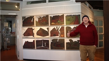 Alexander Dettmar vor einer Bilderreihe in seiner Ausstellung
