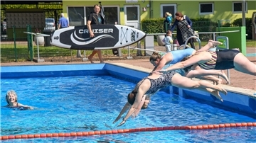 Durchwachsene Saison in Bremerhavens einzigem Freibad Frauen in Badeanzüge springen kopfüber in ein Schwimmbecken.
