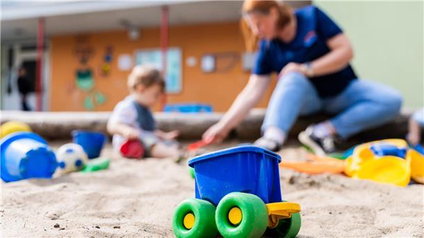 Kita-Förderung verlängert - aber gibt es überhaupt ausreichend Fachkräfte? Bild einer Erzieherin, die mit einem Kind im Sandkasten spielt
