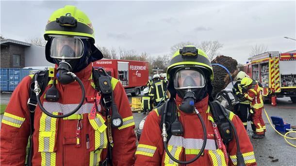Zwei Atemschutzträger sichern den Einsatz am verunglückten Fahrzeug ab. 