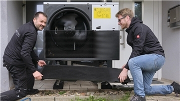 Zwei Fachmänner beim Einbau einer Wärmepumpe. 