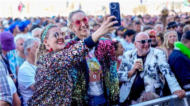 Zwei Festivalbesucherinnen in glitzernden Jacken und Sonnenbrillen.