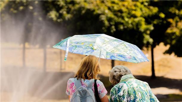 Sommer-Zeit ist Sonnenschutz-Zeit Zwei Frauen schützen mit einem Regenschirm vor der Sonne.