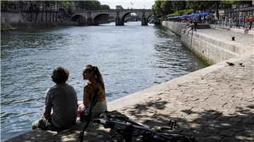 Zwei junge Leute sitzen am Ufer der Seine in Paris.