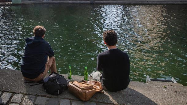 Frankreichs Nationalgetränk gerät aus der Mode Zwei junge Männer trinken am Ufer des Kanals Saint-Martin gemeinsam Bier.
