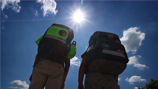 Zwei Kinder laufen mit ihren Schulranzen im Sonnenschein.