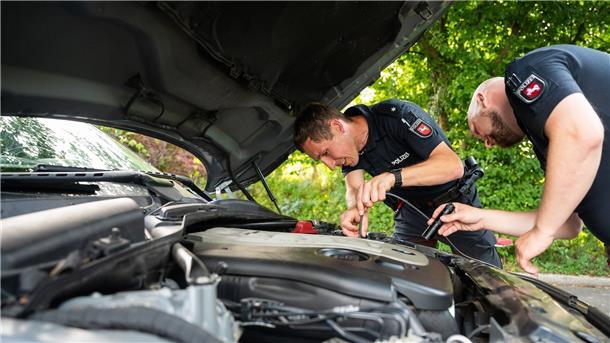 Viele Autoposer beim „Tuning Talk“ der Polizei in Uelzen Zwei Polizisten der Arbeitsgruppe „Auto-Poser“ schauen in den Motorraum eines Fahrzeuges.