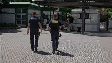 Zwei Polizsten der Mobilen Wache gehen auf das Prinzenbad in Kreuzberg zu.