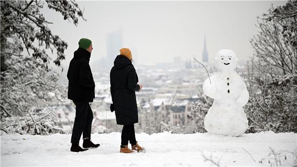 Winteranfang: Glätte und Kälte zum Start in den Dezember Zwei Spaziergänger wandern am Fockeberg (Leipzig) an einem Schneemann vorbei.