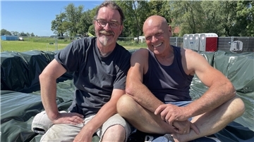 Gernot Bieber und Frerk Francksen, die hier auf dem gerade fertig gebauten Pool aus Heurundballen und Silofolie sitzen, sind die Erfinder und Veranstalter des Butjadinger Festivals Rock on Isens.