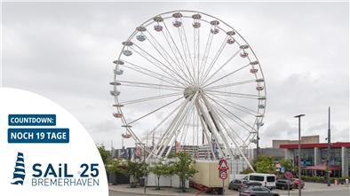 Ein Riesenrad steht in einer Stadt. Der Himmel ist bedeckt.